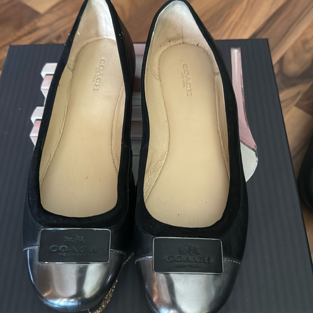 Black coach flats with metallic round toe in excellent condition.